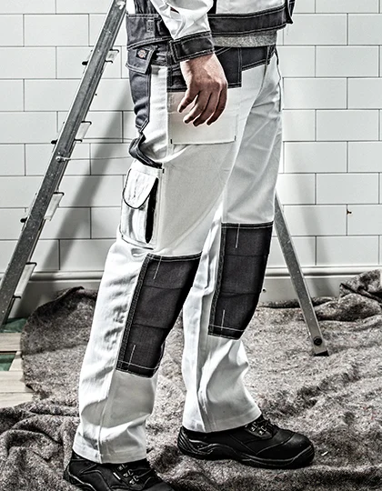 Pantalon de travail blanc et gris avec poches genouillères, porté sur un chantier